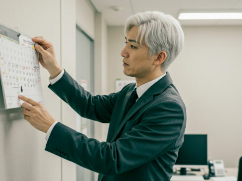 カレンダーを見て仕事を振り返る男性 AI生成